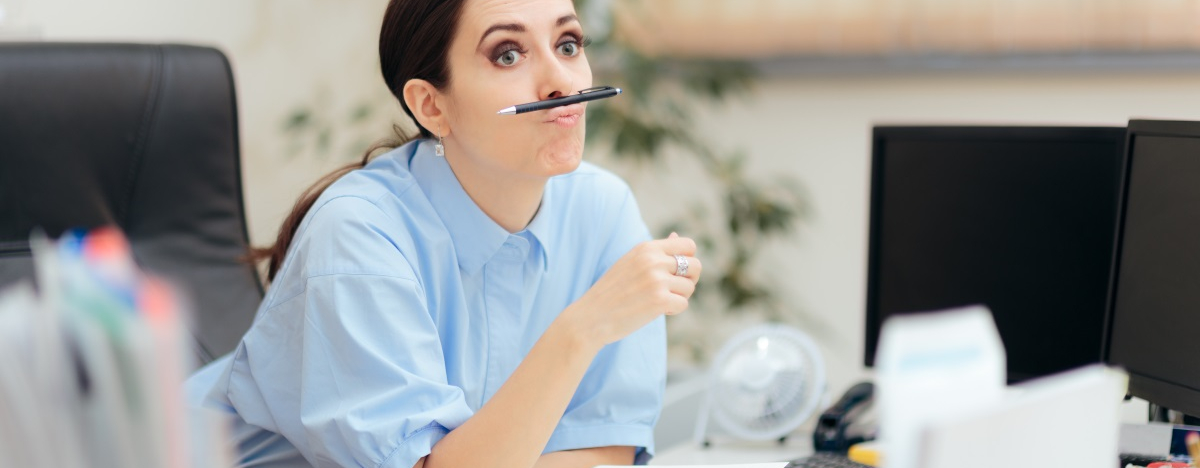 Gelangweilte Mitarbeiterin, die einen Stift auf den Lippen balanciert