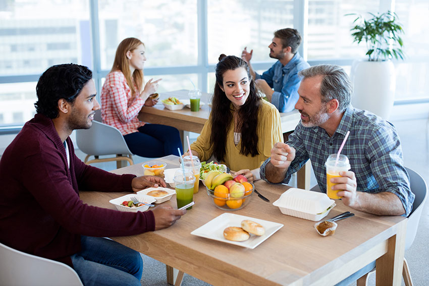 Kollegen beim Mittagessen mit gesundem Essen in der Kantine