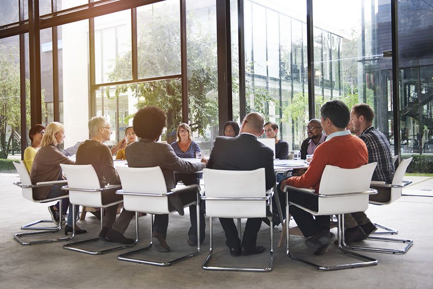 Gr&ouml;&szlig;ere Gruppe sitzt im Kreis am Fenster in einem Seminarraum