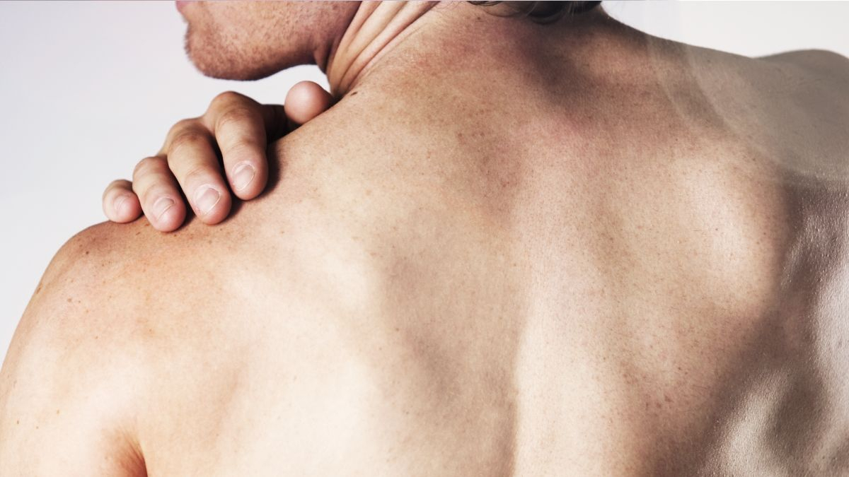 Mann von hinten fasst sich mit der Hand an die Schulter