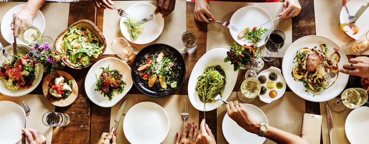 Draufsicht auf einen Tisch, der mit Tellern und Sch&uuml;sseln voll Essen gedeckt ist