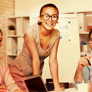 Junge Menschen im B&uuml;ro lachend an einem Tisch