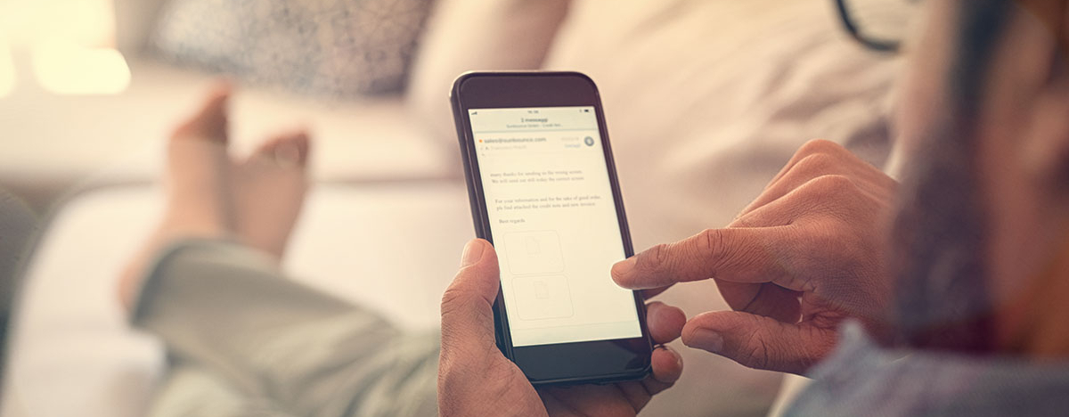 Mann sitzt auf Sofa und tippt auf sein Smartphone
