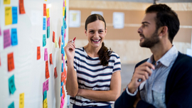 Frau und Mann vor einem Whiteboard mit Post-its