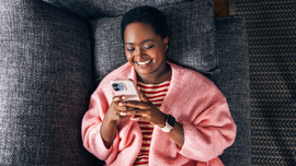 M&auml;dchen liegt auf Sofa und sieht auf ihr Handy