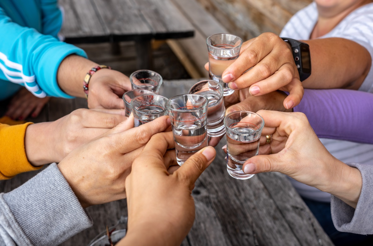 Mehrere H&auml;nde prosten mit Schnapsgl&auml;sern