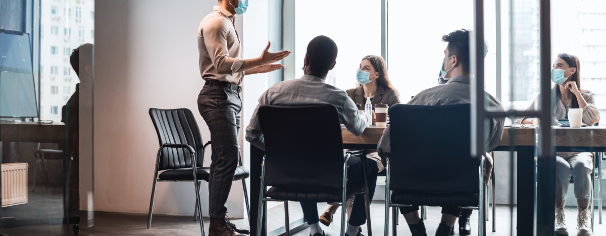F&uuml;nf Personen f&uuml;hren ein Meeting mit Maske durch
