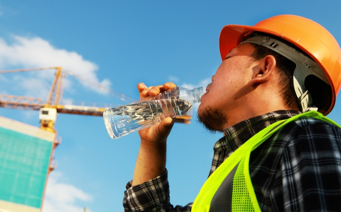 Bauarbeiter trinkt Wasser an einem hei&szlig;en Tag