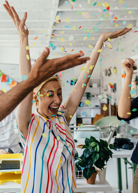 Eine Gruppe B&uuml;ro-Mitarbeiter wirft Konfetti in die Luft