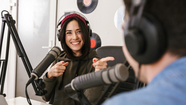 Frau und Mann sitzen in einem Tonstudio vor Mikrofonen