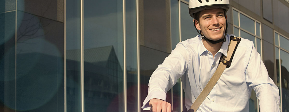 Business Mann f&auml;hrt Fahrrad und hat einen Helm auf