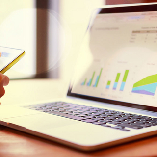 BKK VBU Tools Arbeitshilfen: Frau tippt auf Smartphone vor Laptop-Monitor