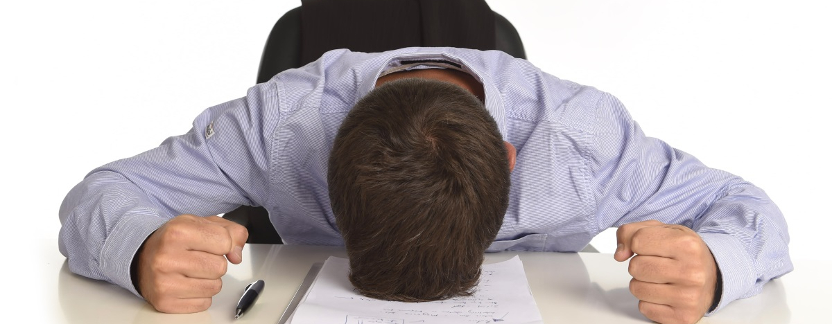 Mann mit geballten F&auml;usten liegt auf Schreibtisch