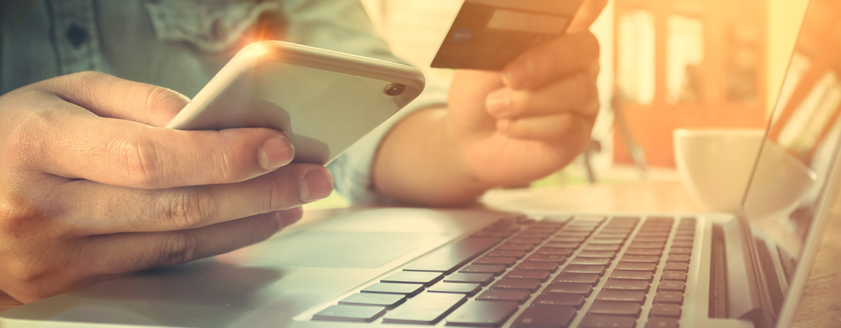 Mann mit Handy und Bankkarte, der eine Online-&Uuml;berweisung macht