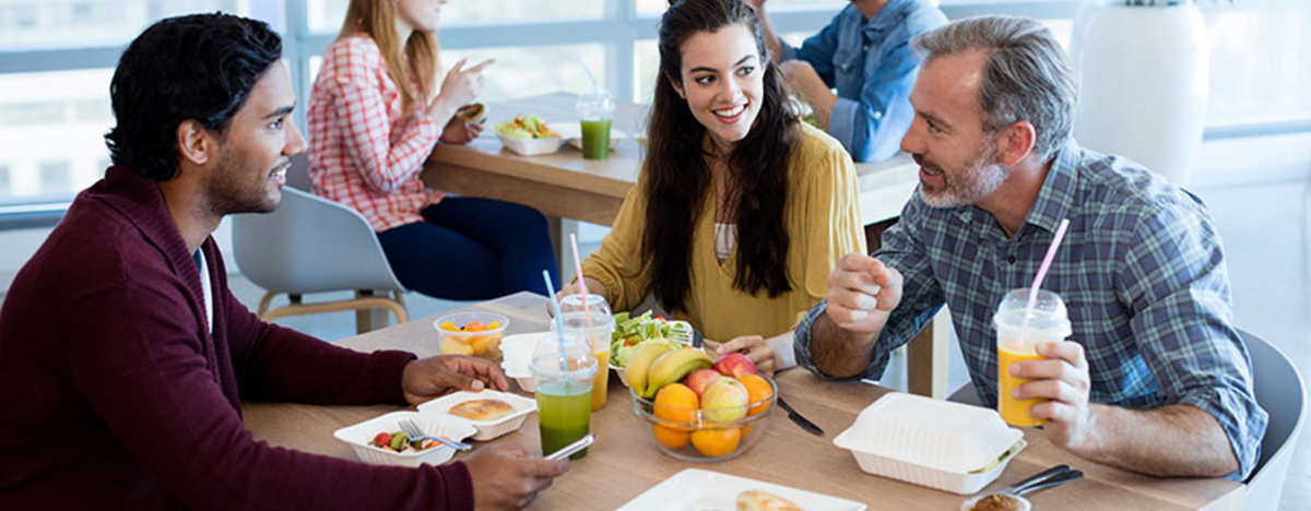 Kollegen beim Mittagessen mit gesundem Essen in der Kantine