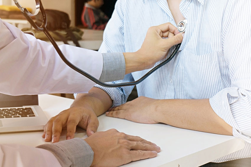 Hand des Arztes legt ein Stetoskop an den Brustkorb einer Frau