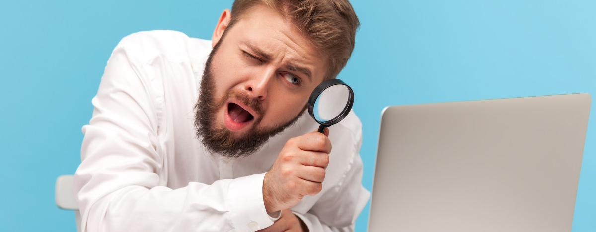 Mann untersucht Bildschirm mit Lupe