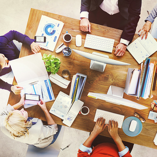 Kollegen am Arbeitstisch mit PC und Material von oben