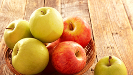 Kleiner Korb mit gr&uuml;nen und roten &Auml;pfeln auf einem Holztisch