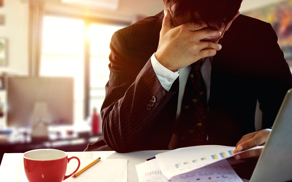 Mann sitzt gestresst am Schreibtisch