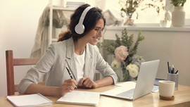 Frau sitzt daheim am Schreibtisch und nimmt an einem Seminar teil