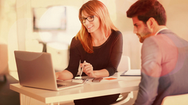 Frau und Mann sitzen am B&uuml;rotisch und blicken gemeinsam auf Computerbildschirm