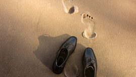 Business-Schuhe und Fußspuren im Sand