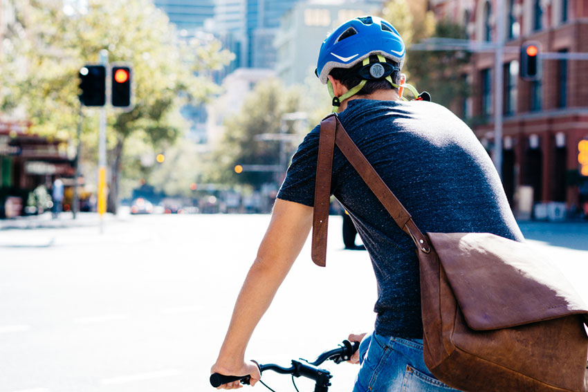 Mann f&auml;hrt mit Helm und Schultertasche auf dem Fahrrad