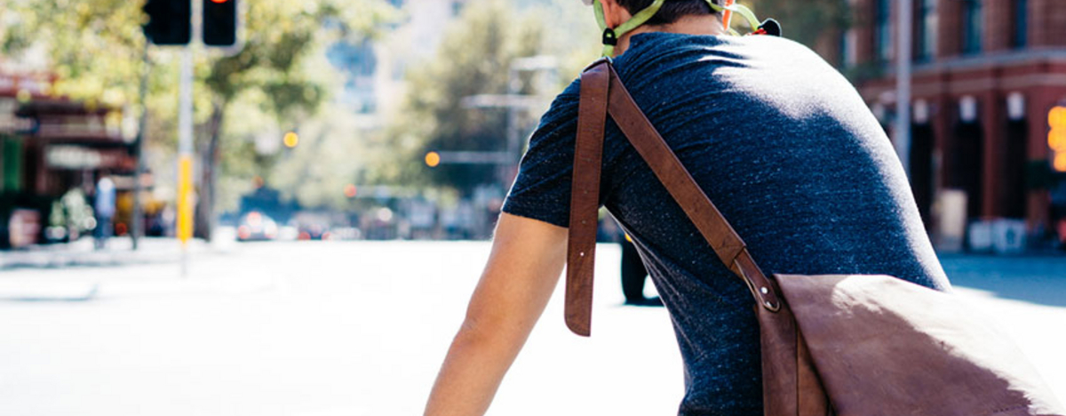 Mann f&auml;hrt mit Helm und Schultertasche auf dem Fahrrad
