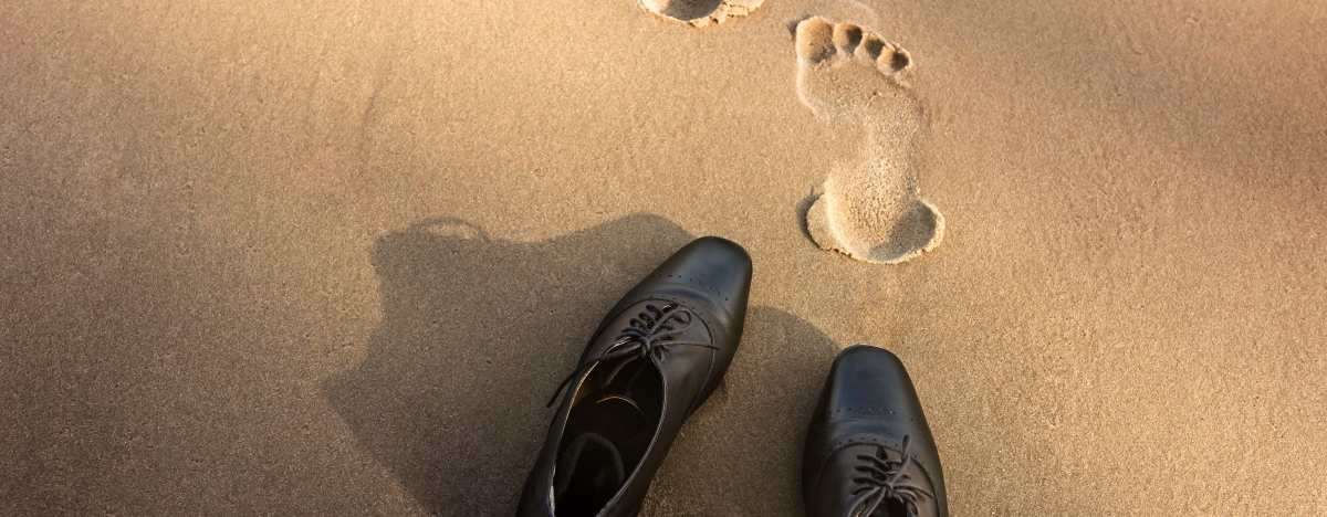 Business-Schuhe und Fu&szlig;spuren im Sand