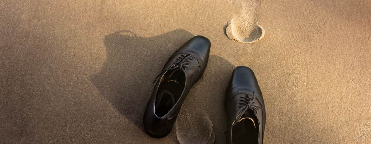 Business-Schuhe und Fu&szlig;spuren im Sand