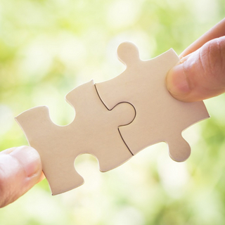 Zu sehen sind zwei H&auml;nde, die zwei passende Puzzleteile zusammenstecken.