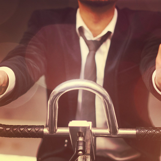 Mann im Anzug sitzt auf Ergometer